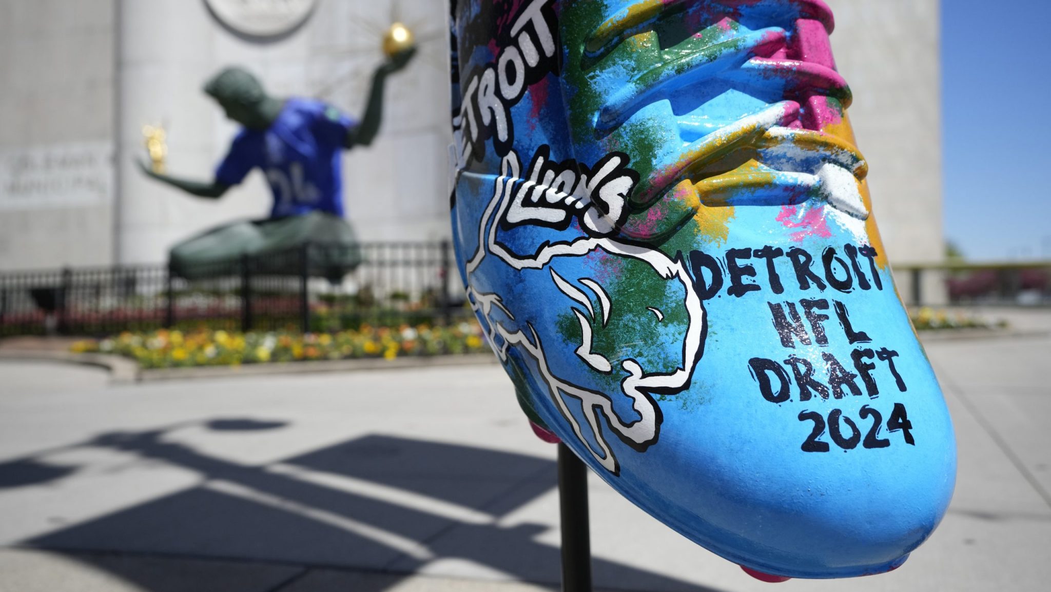 An NFL football draft cleat is displayed near the Spirit of Detroit statue, Friday, April 19, 2024, in Detroit. The draft has taken the show on the road for a decade, giving cities a chance around the country a chance to be in the spotlight.