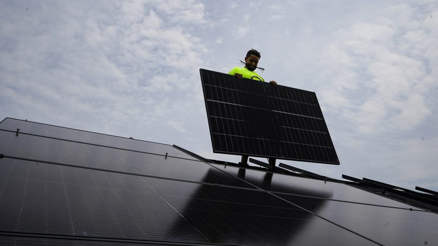 Nicholas Hartnett, owner of Pure Power Solar, holds a panel as his company installs a solar array on the roof of a home in Frankfort, Ky., July 17, 2023. (AP Photo/Michael Conroy, File)