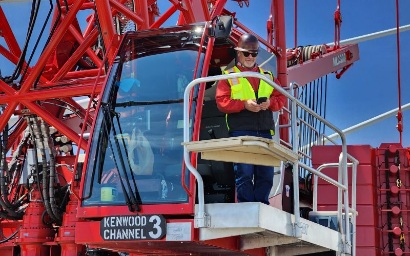 A crane operator stands outside the cockpit on the Gordie Howe International Bridge.