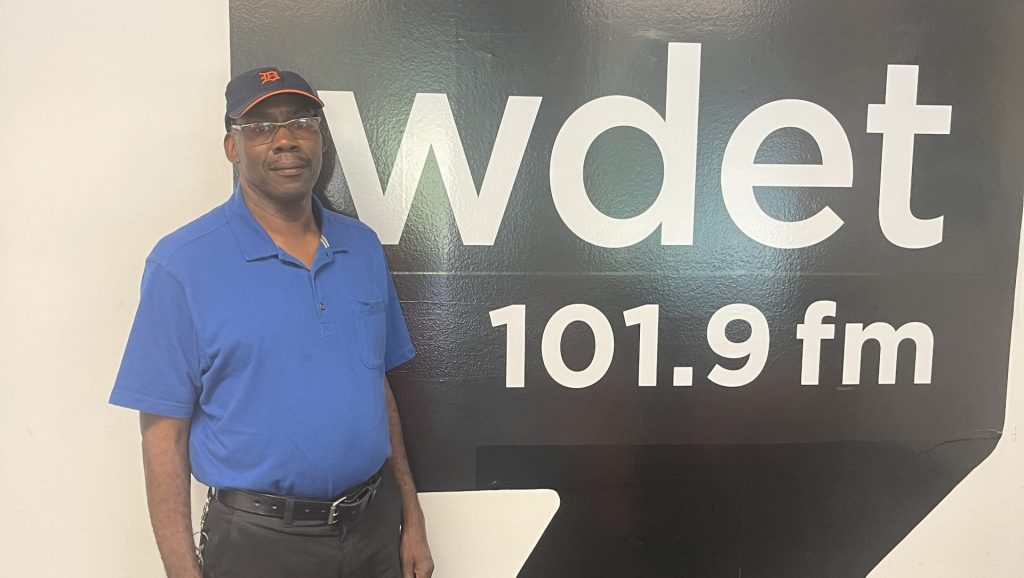 Dwydell Garrett poses in front of a WDET logo.