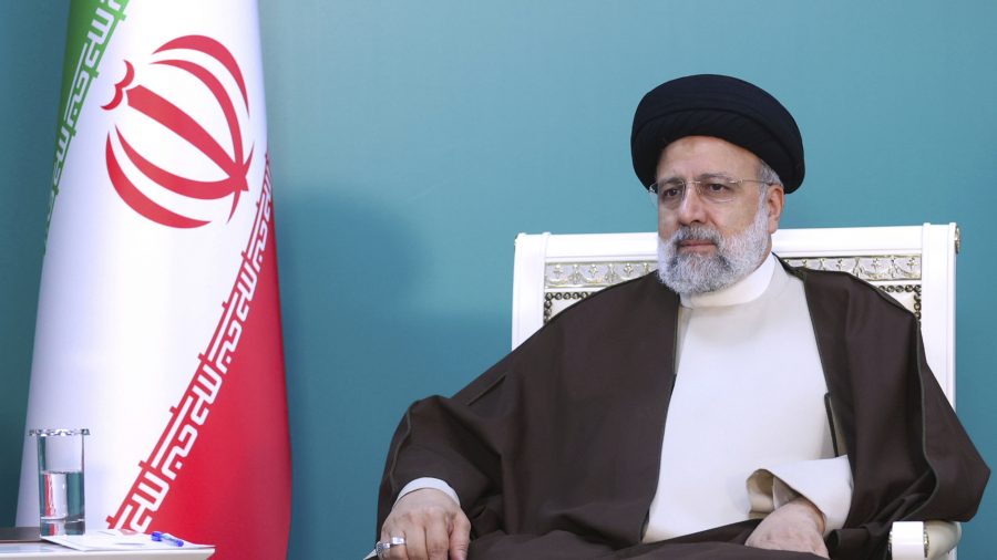 Iranian President Ebrahim Raisi sitting by Iranian flag.