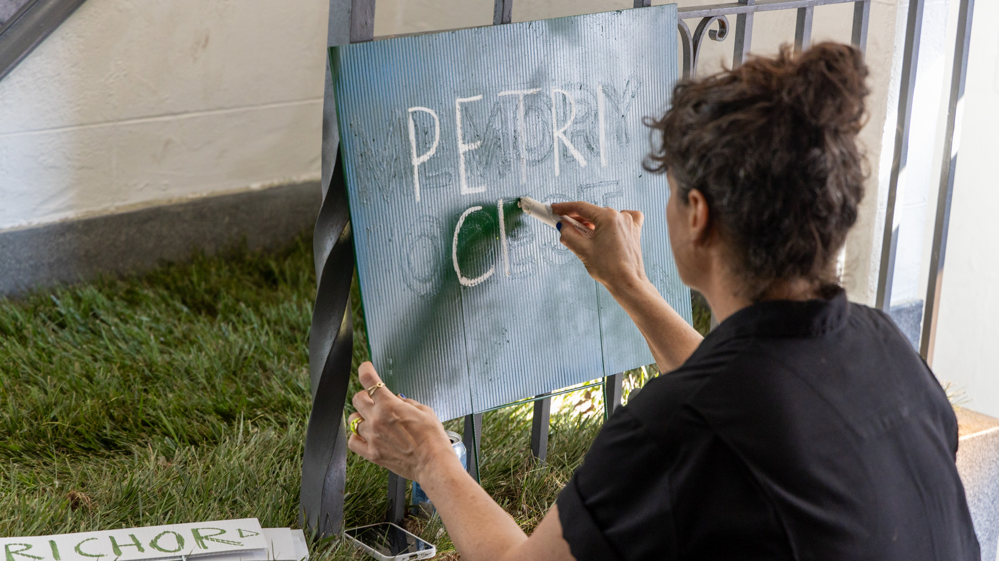 Artist Lisa Waud writes on a sign inside the Boyer Campbell Building in Detroit for her Petrichor botanical art installation on May 30, 2024. (Photo credit: Tayler Simpson, WDET)