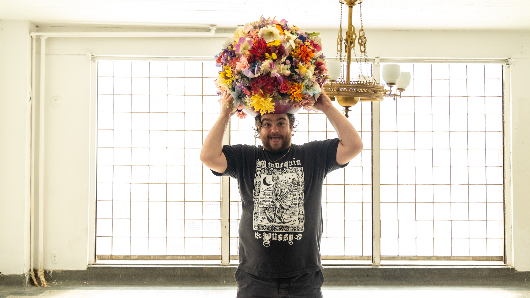 WDET host Ryan Patrick Hooper holding a flower headdress created by artist Lisa Waud at her "Portrait" art installation at the Boyer Campbell building in Detroit on June 26, 2024. (Photo by Tayler Simpson, WDET)