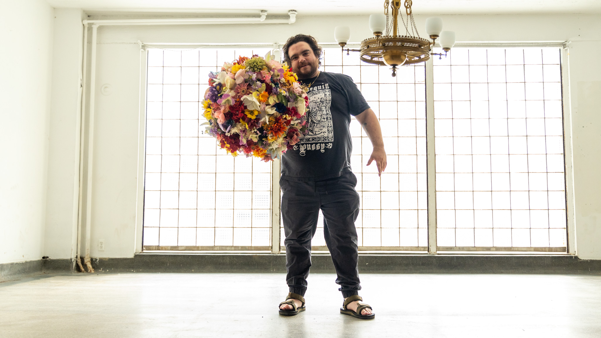 WDET host Ryan Patrick Hooper holding a flower headdress created by artist Lisa Waud at her "Portrait" art installation at the Boyer Campbell building in Detroit on June 26, 2024.