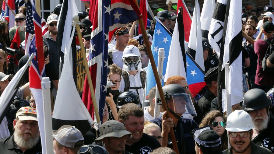 FILE - White nationalist demonstrators walk into the entrance of Lee Park surrounded by counter demonstrators in Charlottesville, Va., Saturday, Aug. 12, 2017.