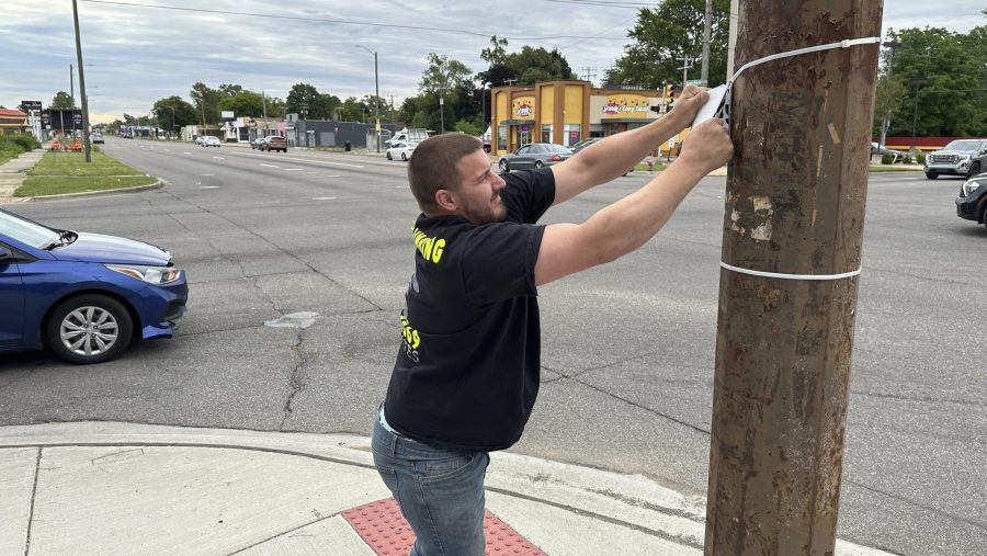 Suburban business owner William Shaw removes illegally posted signs Friday, June 28, 2024, in Detroit, from a street corner in as part of court-ordered community service.