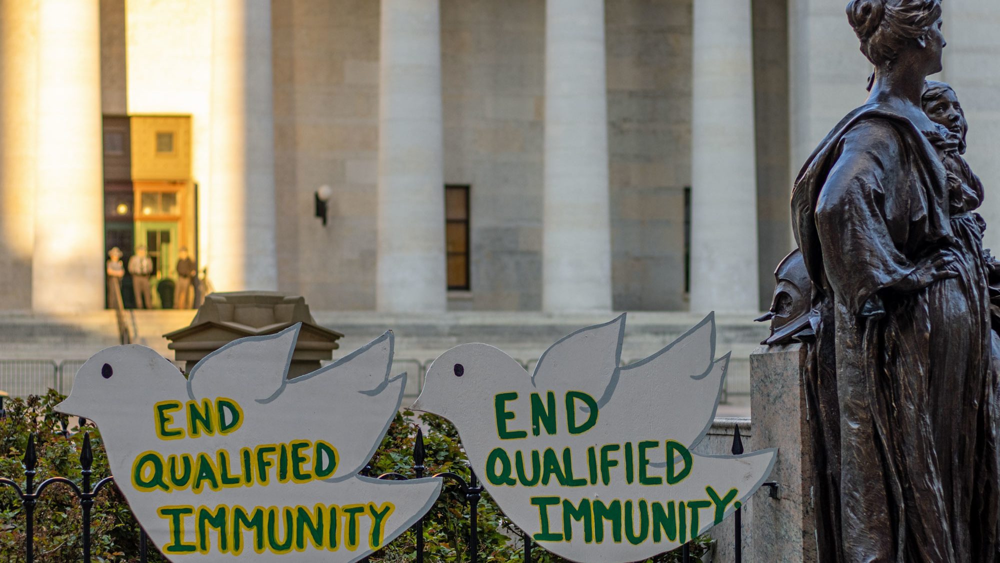 Two signs read "End qualified immunity" during a Black Lives Matter protest held outside the Ohio Supreme Court in Columbus, Ohio, July 2021.