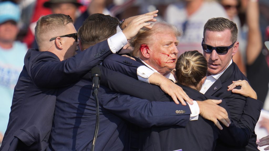 Republican presidential candidate former President Donald Trump is surrounded by U.S. Secret Service agents as he is helped off the stage at a campaign rally in Butler, Pa., Saturday, July 13, 2024. (AP Photo/Gene J. Puskar)