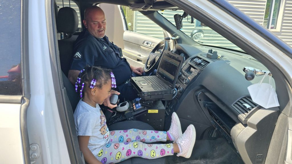 A Detroit police officer shows a young girl the inside of his patrol vehicle.