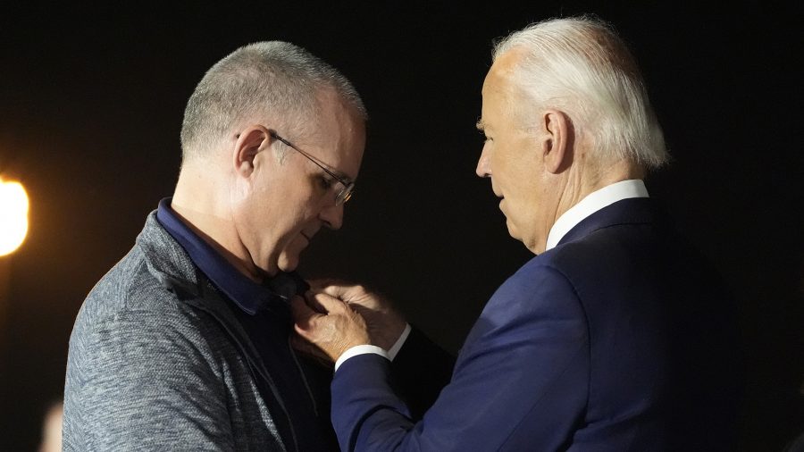 President Joe Biden, right, places his American flag pin on Paul Whelan at Andrews Air Force Base, Md., following Whelan's release as part of a 24-person prisoner swap between Russia and the United States, Thursday, Aug. 1, 2024.