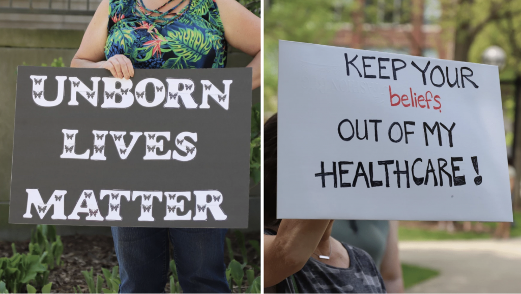 Two women with opposing views hold signs that read "Unborn lives matter" and "Keep your beliefs out of my healthcare."