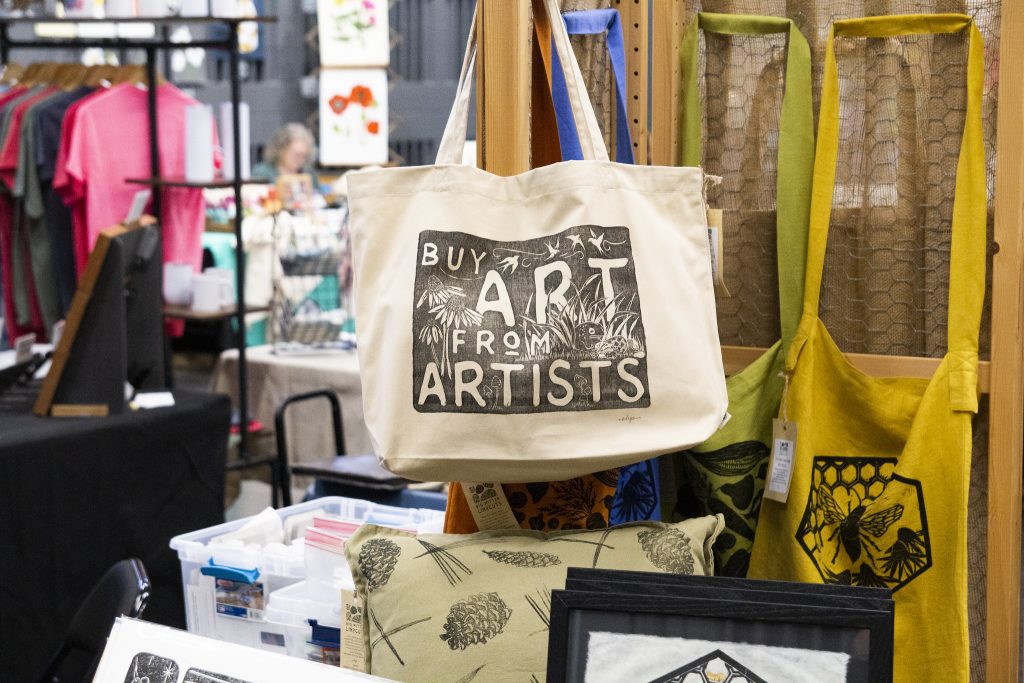 A tote bag with "Buy art from artists" printed on it