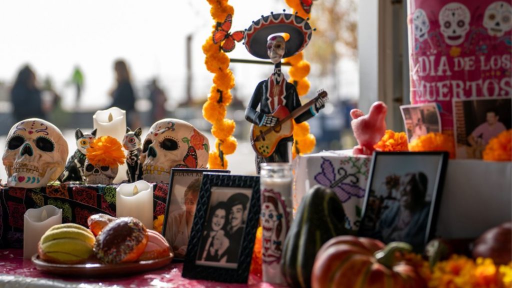 A Día de los Muertos ofrenda featuring pictures, sugar skulls and treats.