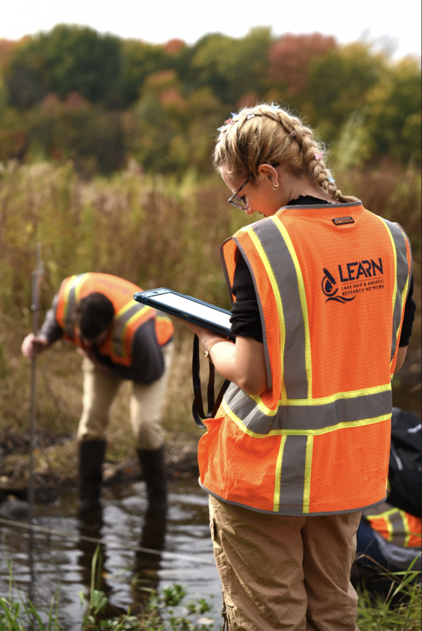 Kent State University graduate student Alex Ochs enters data while H2Ohio Wetland Monitoring Program technician Connor Gluck takes measurements.