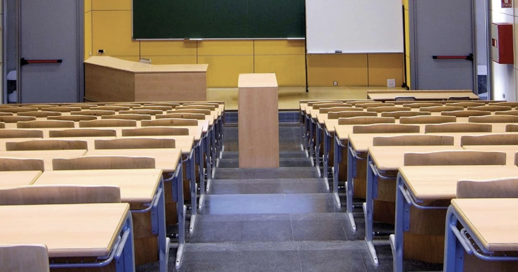 Rows of chairs sit empty in a college classroom.