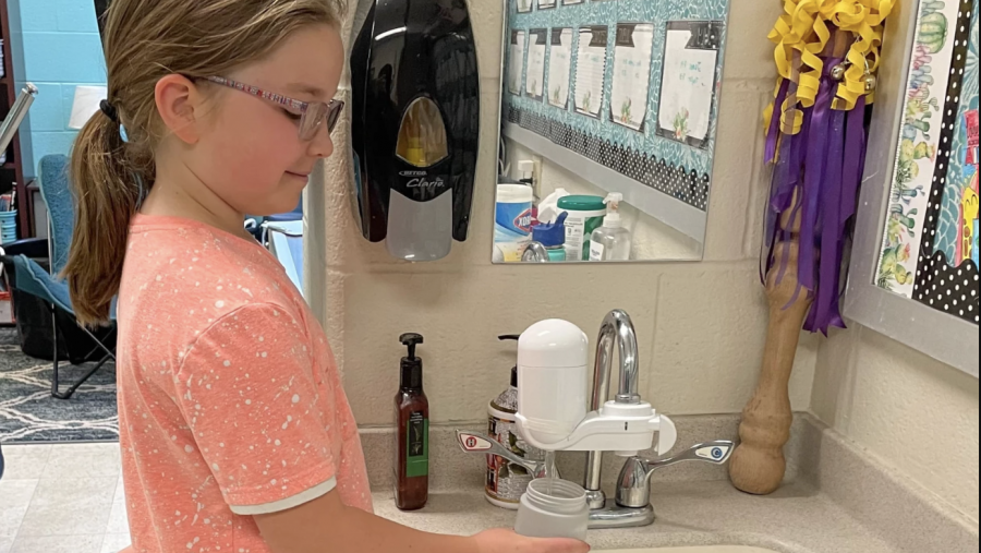 A girl fills a water bottle at a faucet with a mounted filter.