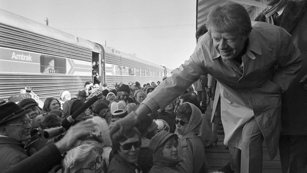 FILE - President-elect Jimmy Carter leans over to shake hands with some of the people riding the "Peanut Special" to Washington, Jan. 19, 1977. They will travel all night, arriving in Washington in time for Carter's inauguration as president on Jan. 20.