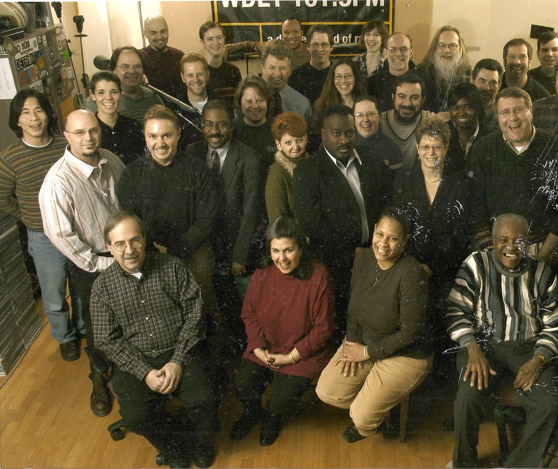 Former WDET Program Director Judy Adams (front and center in red) poses alongside her colleagues at WDET Studios.