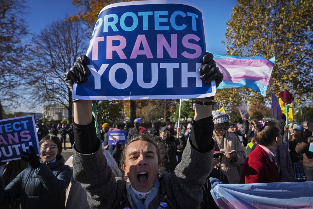 A young person who preferred not to give her name, cheers as supporters of transgender rights rally by the Supreme Court, Wednesday, Dec. 4, 2024, in Washington, while arguments are underway in a case regarding a Tennessee law banning gender-affirming medical care for transgender youth.