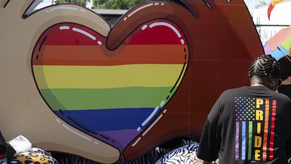 A participant wearing a Pride shirt stands in front of a parade float during the Kentuckiana Pride Parade on Saturday, June 21, 2025, in Louisville, Ky.