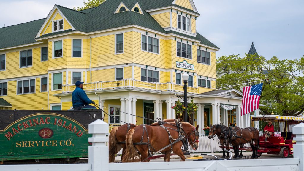 Horses pulling freight and tourists pass in front of the Windermere Hotel on Mackinac Island.