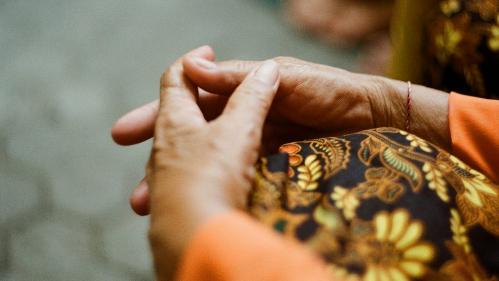 A women's hands are wrap around her knee as she is seated.