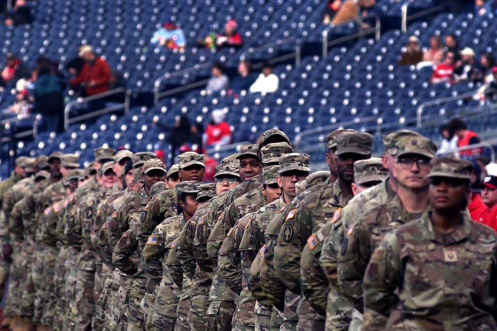 Row of uniformed men and women walk through the baseball stadium