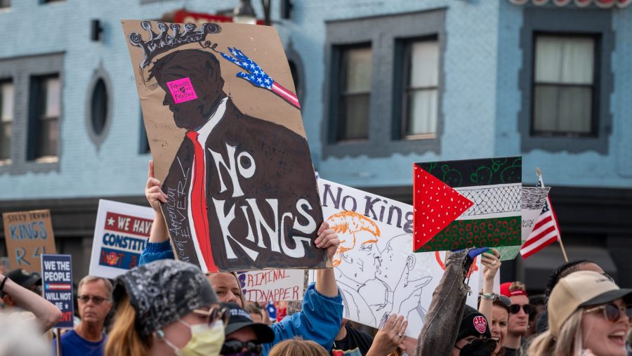 Protesters hold signs that say, "No kings" and Palestinian flags