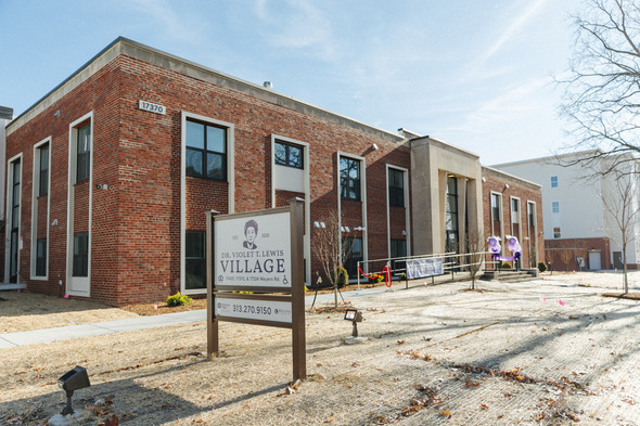 A brick apartment complex designed for seniors. A sign outside depicts Violet T. Lewis.