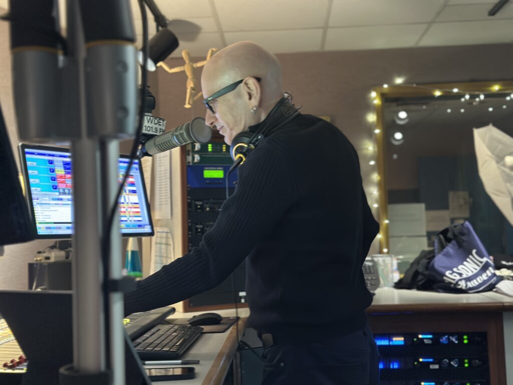 Big Sonic Heaven host Darren Revell stands at the sound board in WDET's main studio.