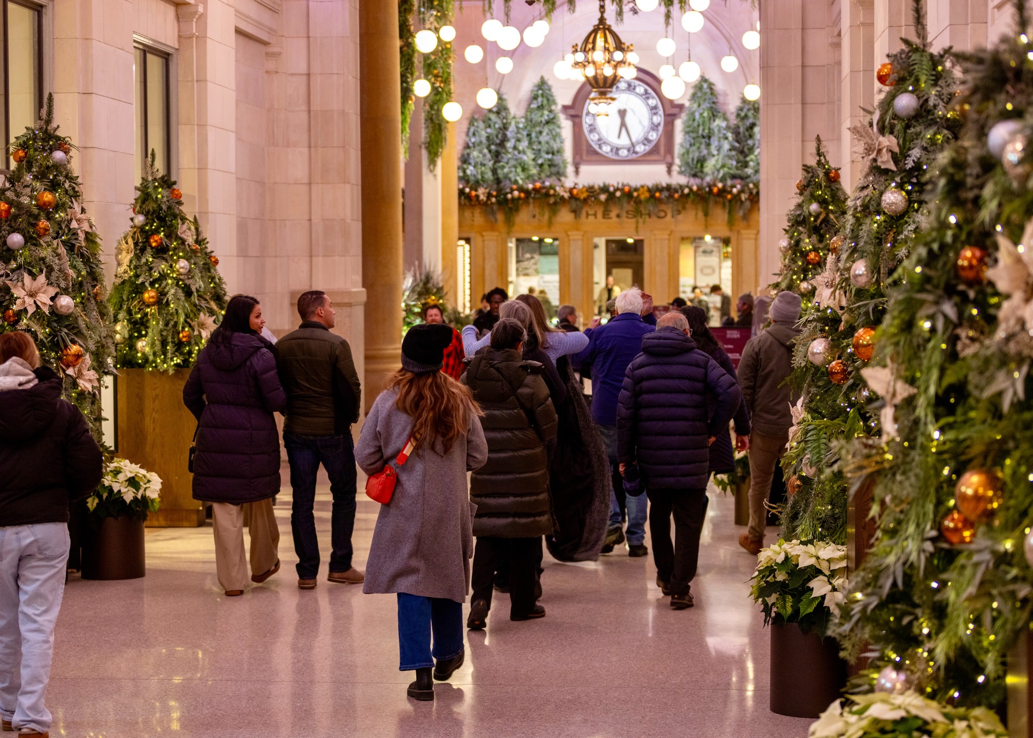 People walk through holiday decorations at Michigan Central Station